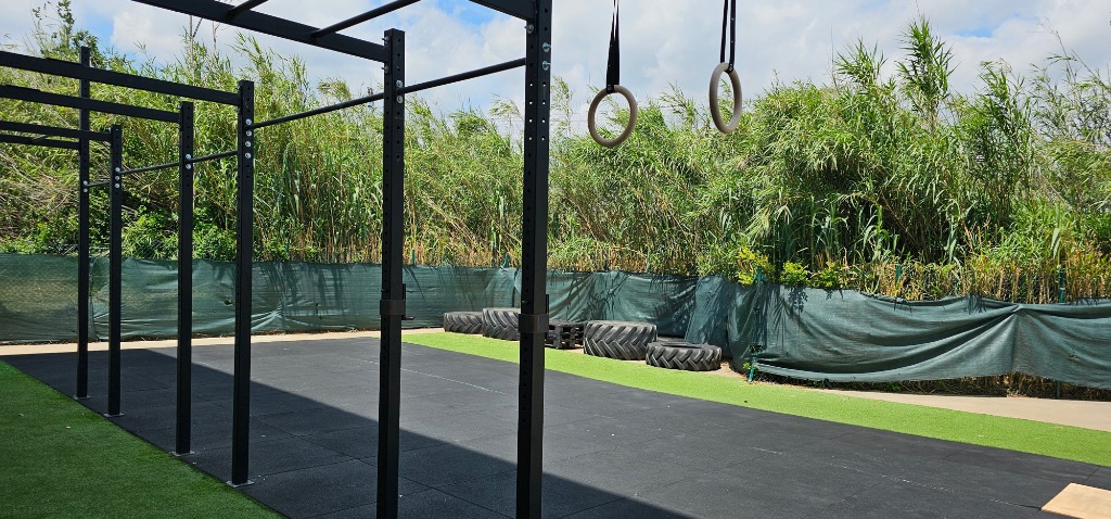 Zona outdoor de Siron Fitness Club con estructura de calistenia, anillas y césped