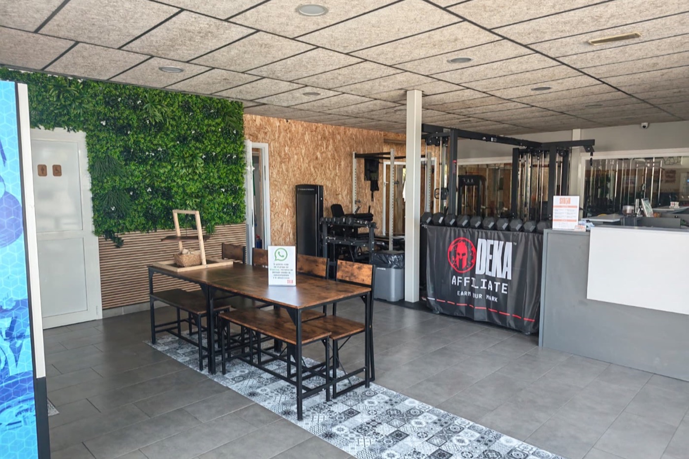 Recepción de Siron Fitness Club con la mesa larga del comedor y la pared vegetal